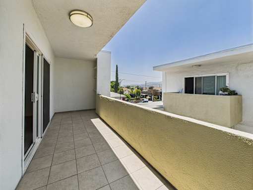 A balcony with a tan wall and tiled floor.