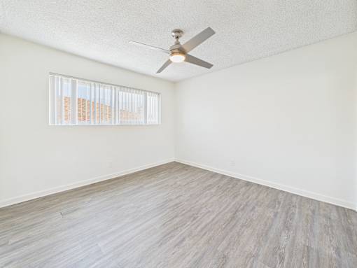 A room with a ceiling fan and a window with blinds.
