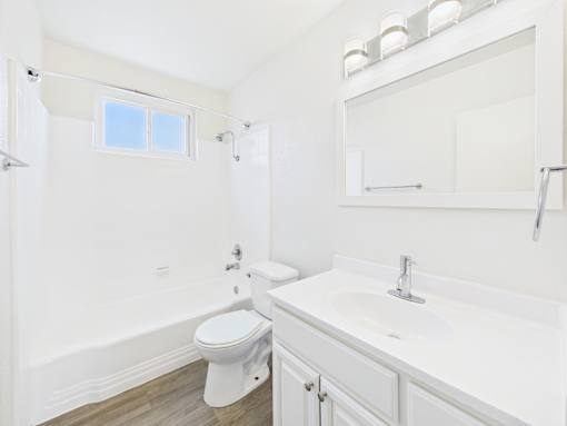 A white bathroom with a toilet, sink, and bathtub.