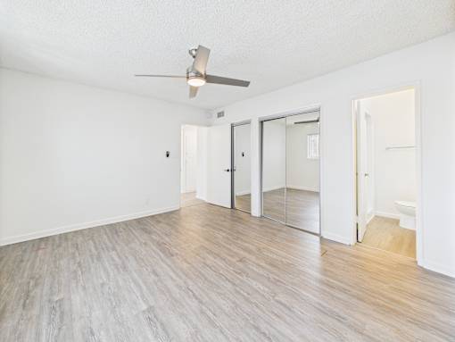 A room with a ceiling fan and wooden flooring.