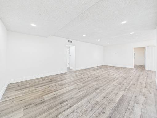 A room with wooden flooring and white walls.