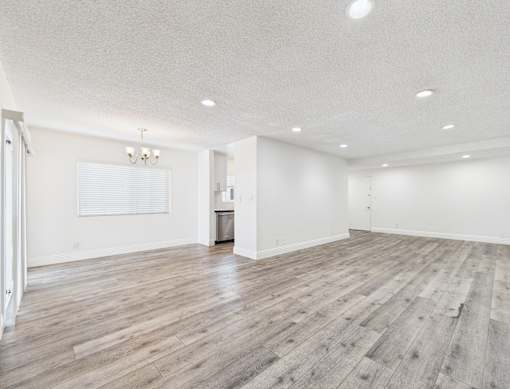 A spacious room with wooden flooring and white walls.