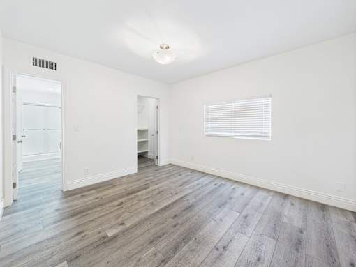 A room with wooden flooring and white walls.