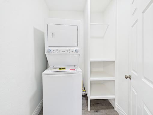 A white dishwasher is in a narrow hallway with a white door on the right.