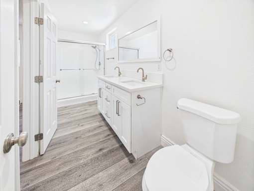 A white bathroom with a toilet, sink, and mirror.
