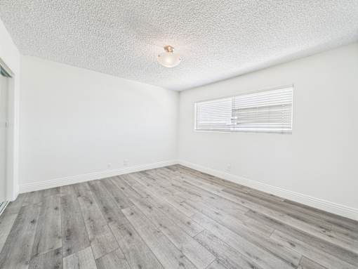 A room with wooden flooring and a window with blinds.