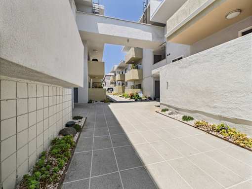 A long, narrow courtyard with a tiled floor and white walls.