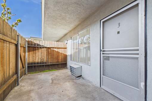 A patio area with a white door and a window with blinds.