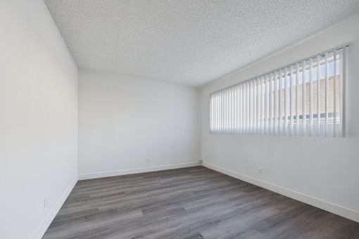 A room with a window covered by white blinds.