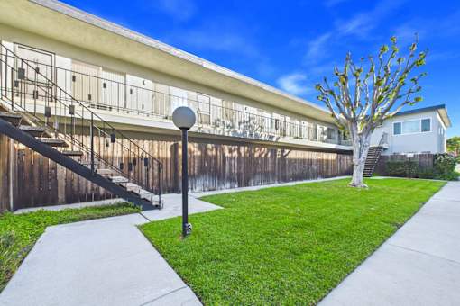 A building with a wooden fence and a tree in front.
