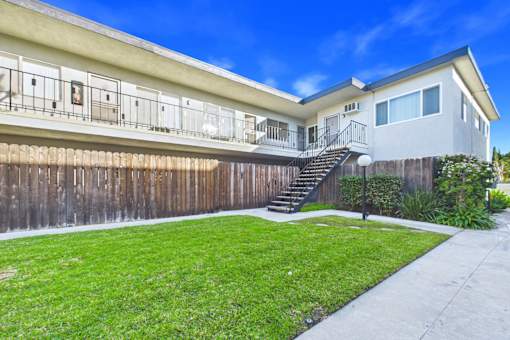 A house with a wooden fence and a green lawn.