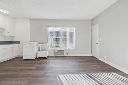 A kitchen with white appliances and a window with blinds.
