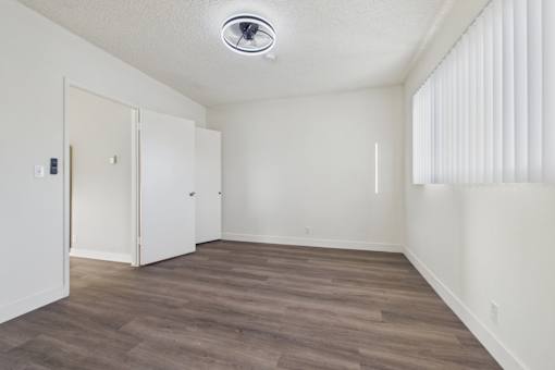 A room with a white ceiling and wooden flooring with two doors.