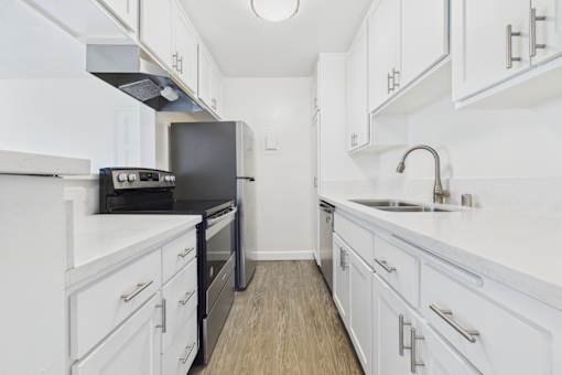 A kitchen with white cabinets and a black stove top oven.