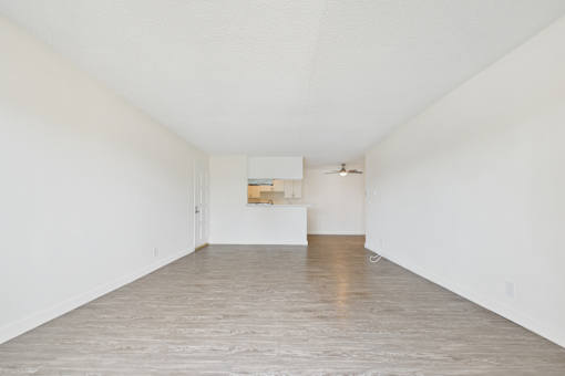 A room with white walls and wooden flooring with a white box on the floor.