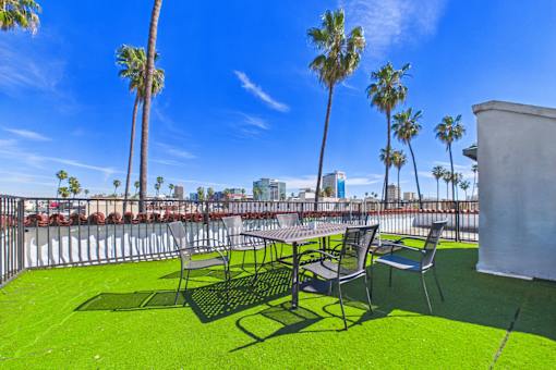 A patio with a table and chairs overlooking a beach.