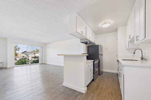 A kitchen with white cabinets and a black fridge.