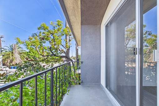 A balcony with a metal railing and glass doors overlooking a garden.