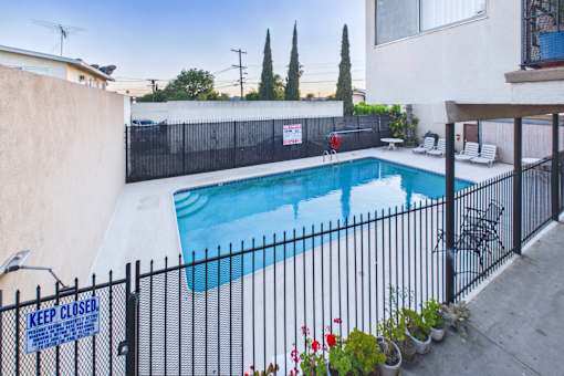 A pool surrounded by a black fence with a sign that says "Keep Closed".