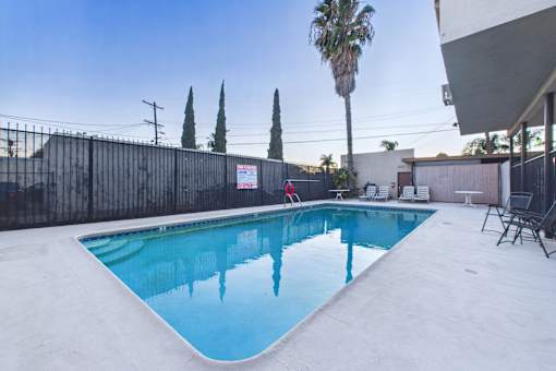 A pool with a fence and trees in the background.