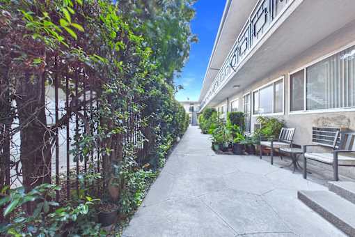 A concrete pathway leads to a building with a balcony.