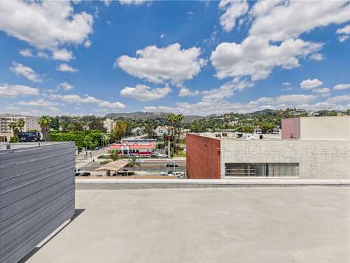 A view from a rooftop of a cityscape with buildings and a parking lot.