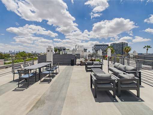 A rooftop patio with a table and chairs overlooking a city skyline.