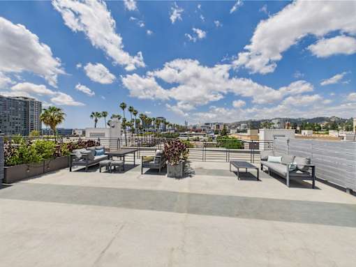 A rooftop patio with a couch, chairs, and a table.