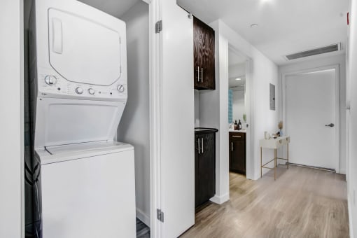 a white washer and dryer in a room with a bathroom and a kitchen