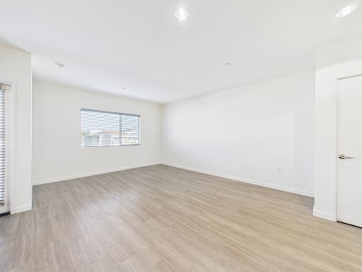 A room with light wood flooring and white walls.