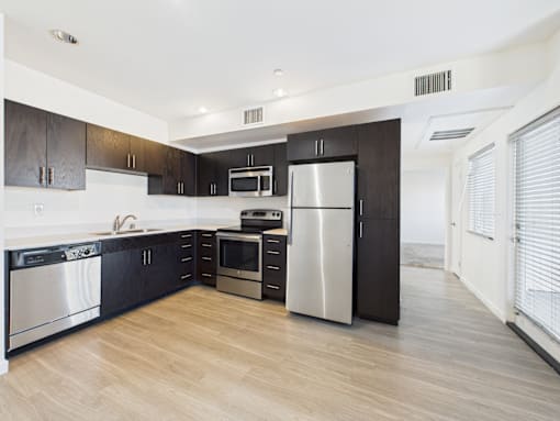 A modern kitchen with black cabinets and stainless steel appliances.