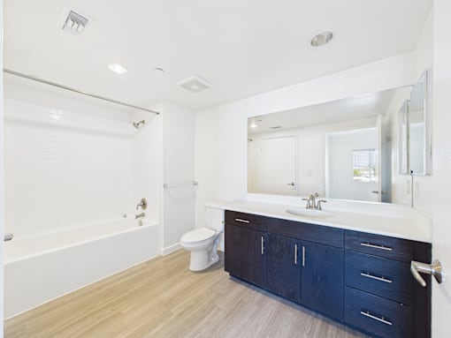 A white bathroom with a blue cabinet.