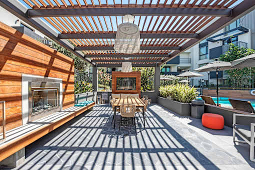 A patio with a table and chairs and a fireplace.