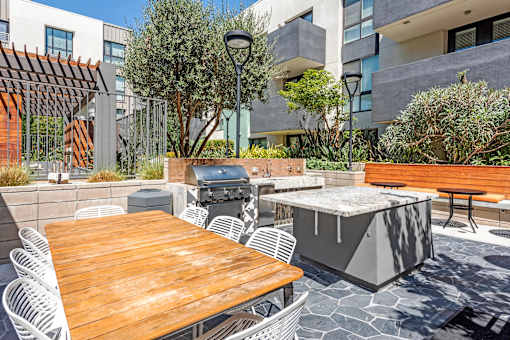 A patio with a table, chairs, and a grill.