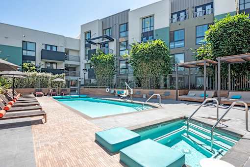 A large outdoor swimming pool surrounded by wooden decking and sun loungers.