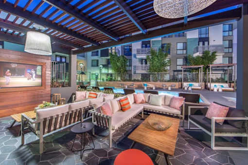A patio with a table and chairs and a screen on the wall.