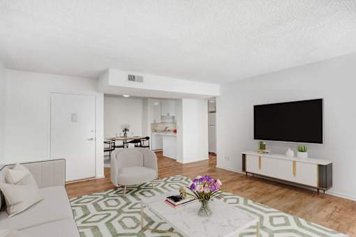 A living room with a white couch, a white chair, a white coffee table, a white cabinet, a white TV, a white rug, and a white wall.