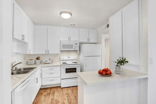A kitchen with white cabinets and appliances.