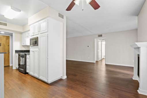 an empty living room with white cabinets and a wood floor