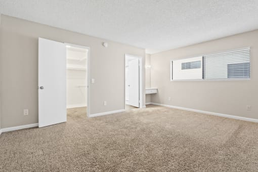 the spacious living room of an apartment with carpet and an open door to the bathroom