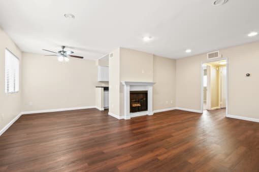an empty living room with a fireplace and a ceiling fan