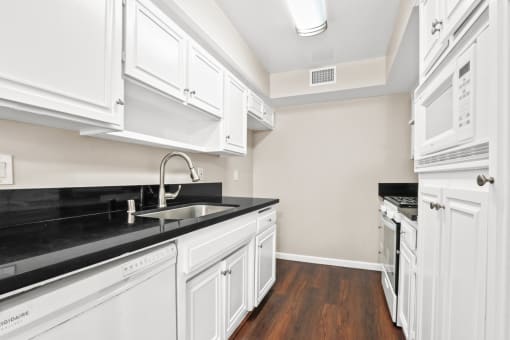 a kitchen with white cabinets and black counter tops and a sink