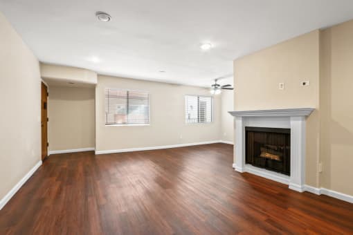 an empty living room with a fireplace and wooden floors