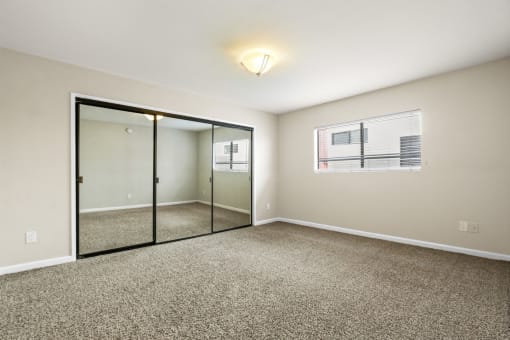 an empty living room with mirrored doors and carpeting