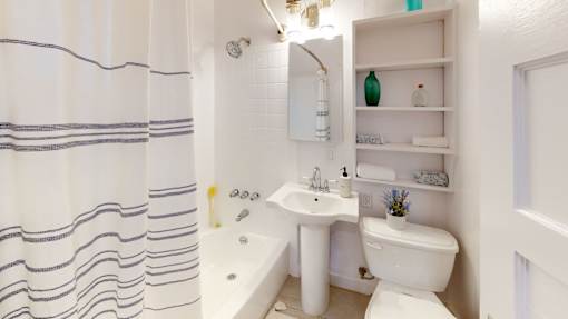 A white bathroom with a white toilet, sink, and bathtub.