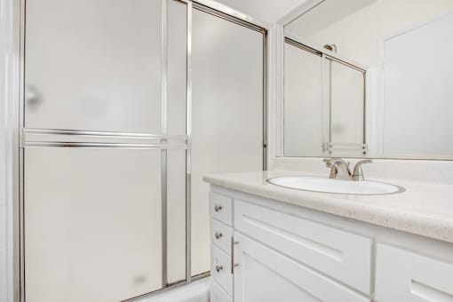 A white bathroom with a sink and a shower.
