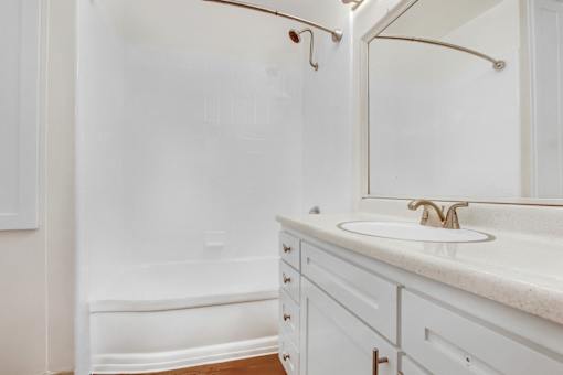A white bathroom with a tub, sink and mirror.