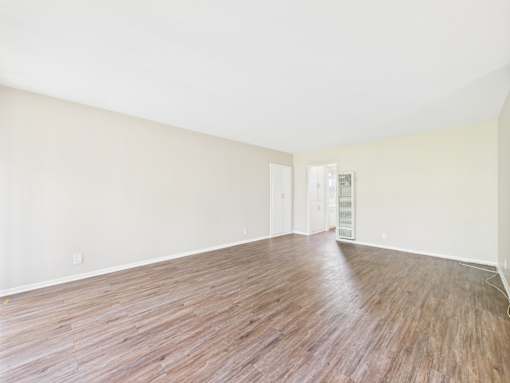 Empty room with wooden flooring and white walls.