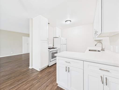 A kitchen with white cabinets and a wooden floor.