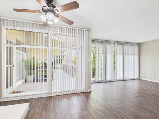 A room with a ceiling fan and sliding glass doors.